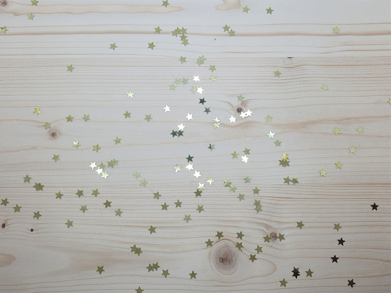 Glitzerstere auf einem Holzebrett symbolisieren den Zauber des Schenkens.